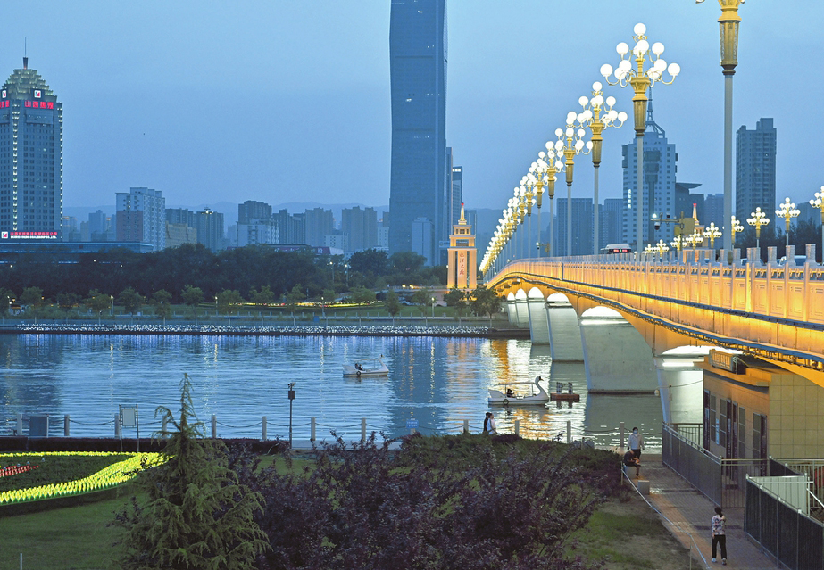 迎泽大桥灯光璀璨，水面倒映城市夜景，船只穿梭其间，勾勒出温馨的都市夜色画卷。